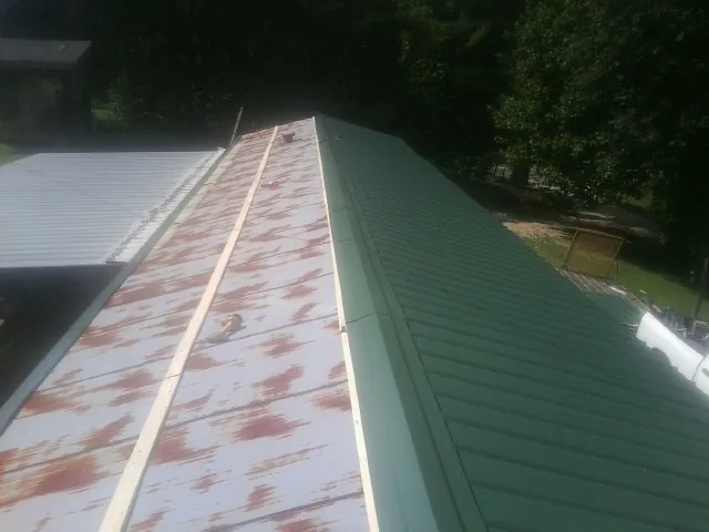 Old rusted panels beside newly installed green metal roofing — Wind Damage Roof Repair by Roofing Brothers in Dixon